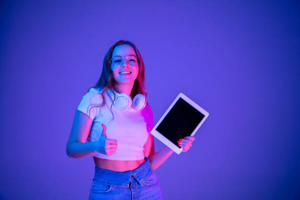 istock Caucasian woman's portrait isolated on blue studio background in multicolored neon light 1302961040