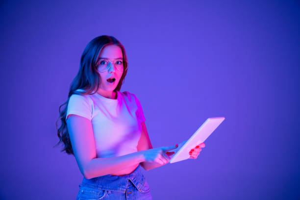 istock Caucasian woman's portrait isolated on blue studio background in multicolored neon light 1302961043