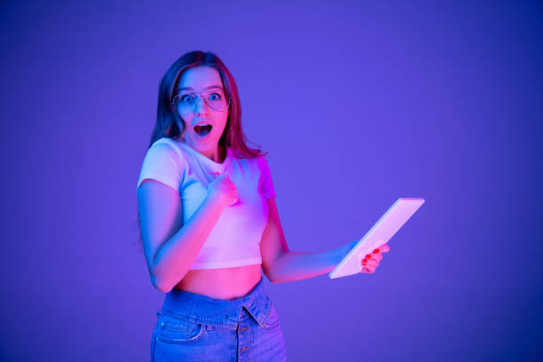 istock Caucasian woman's portrait isolated on blue studio background in multicolored neon light 1302961045