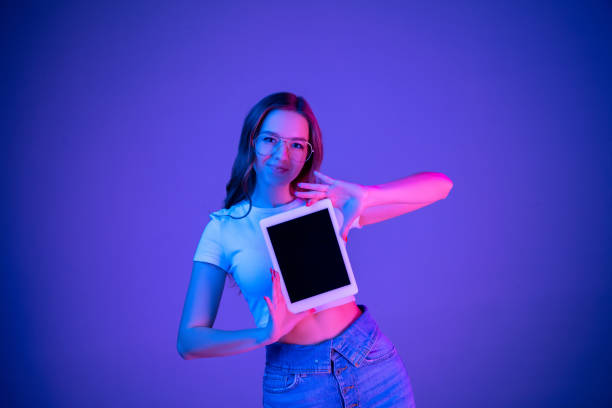 Caucasian woman's portrait isolated on blue studio background in multicolored neon light
