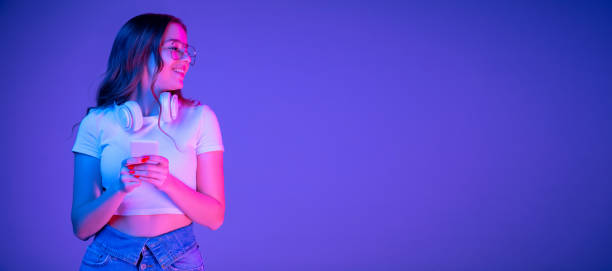 Caucasian woman's portrait isolated on blue studio background in multicolored neon light