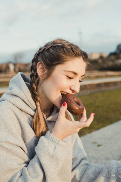 istock Young woman eating a chocolate doughnut 1302963738