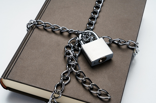 Hardback book and padlock on white background