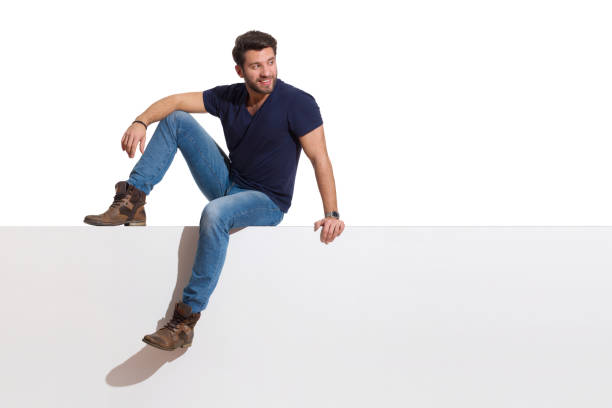 istock Casual Youngl Man Is Sitting Relaxed On A Top, Looking Away And Smiling 1302964893