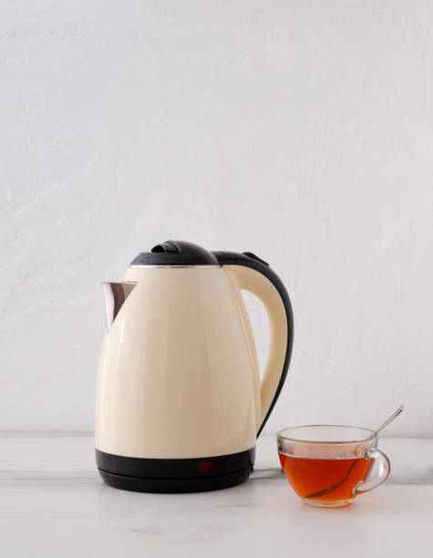 istock Vertical image.Beige kettle and glass cup of black tea on the kitchen table 1302965412