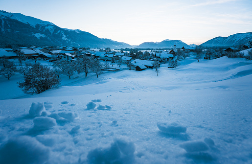 Winter mountian landscape during blue hour dusk with view over small Austrian traditional village in Wildermieming, Tyrol, Austria