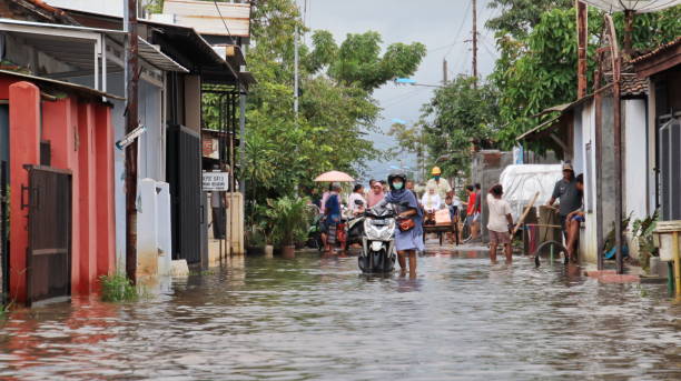 residenti mentre attraversano un'inondazione - floodwaters foto e immagini stock