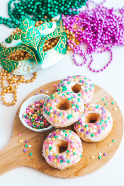 istock Mardi gras carnival sprinkled doughnuts and beads, holiday celebration, baking, top view 1302968774