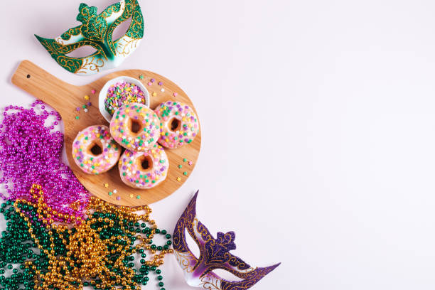 istock Mardi gras carnival sprinkled doughnuts and beads, holiday celebration, baking, top view 1302968778