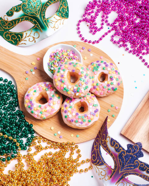 istock Mardi gras carnival sprinkled doughnuts and beads, holiday celebration, baking, top view 1302968786