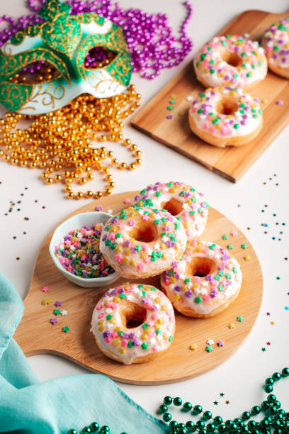 istock Mardi gras carnival sprinkled doughnuts and beads, holiday celebration, baking, top view 1302968796