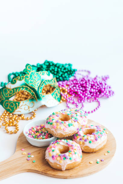 istock Mardi gras carnival sprinkled doughnuts and beads, holiday celebration, baking, top view 1302968809