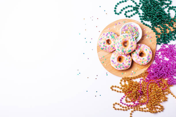istock Mardi gras carnival sprinkled doughnuts and beads, holiday celebration, baking, top view 1302968813