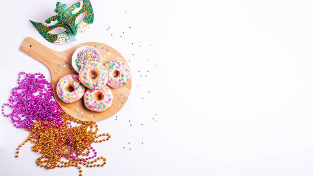 istock Mardi gras carnival sprinkled doughnuts and beads, holiday celebration, baking, top view 1302968818