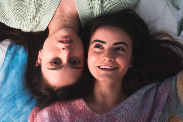 istock Two cute young women laying on a bed 1302969945