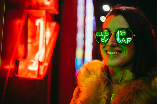 Young Caucasian beautiful woman and neon light on street.