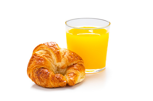 Breakfast: close up view of fresh homemade croissant and an orange juice glass isolated on white background. Predominant colors are yellow and white. High resolution 42Mp studio digital capture taken with Sony A7rII and Sony FE 90mm f2.8 macro G OSS lens