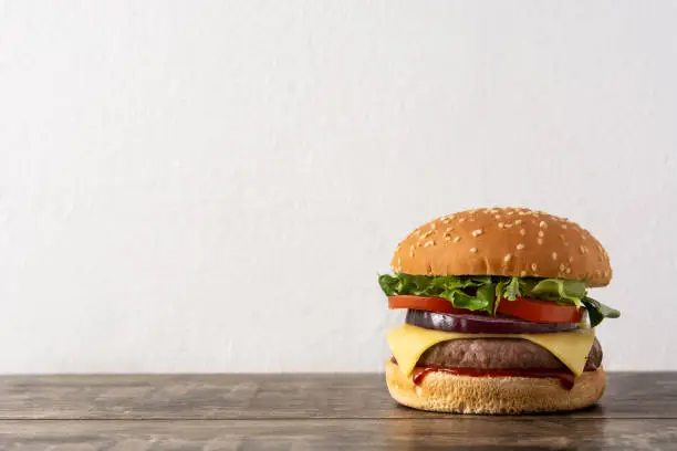 Cheeseburger with beef,tomato, lettuce and onion on wooden table