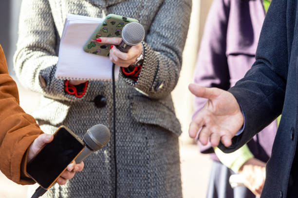 istock Midsection Of People Holding Microphone By Man 1302977709