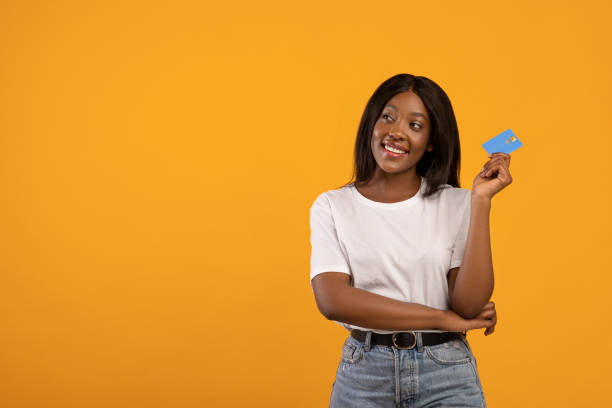 istock Smiling black woman with credit card looking at copy space 1302977947
