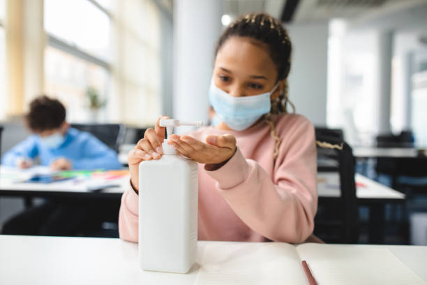 istock Small black girl applying antibacterial sanitizer on hands 1302978331
