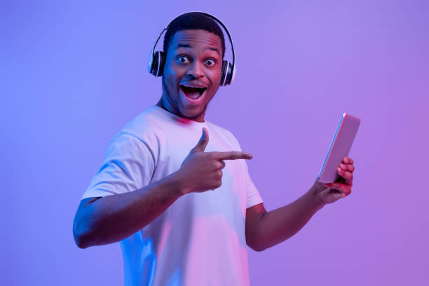 istock Modern Gadgets For Entertainment. Happy black man in headphones using digital tablet 1302978424