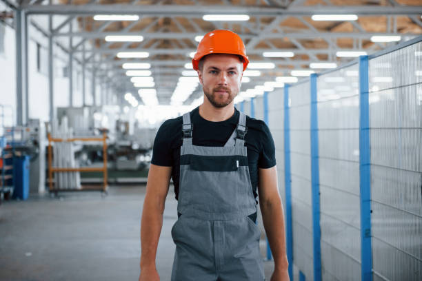 en el futuro. trabajador industrial en el interior de la fábrica. joven técnico con sombrero duro naranja - manual worker portrait helmet technology fotografías e imágenes de stock