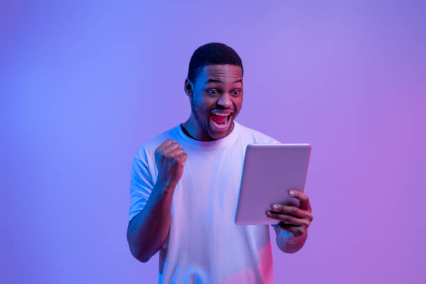 istock Online Win. Joyful African American Guy Celebrating Success With Digital Tablet, 1302981411