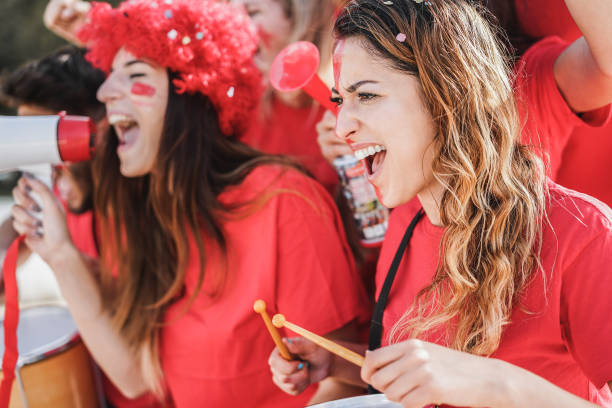 istock Crazy football supporters playing drums and screaming while supporting their team - Focus on right woman 1302982750