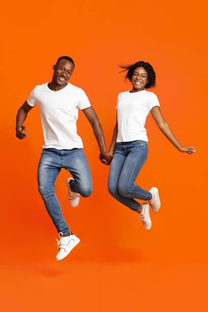 istock Happy black lovers holding hands and jumping up 1302983809