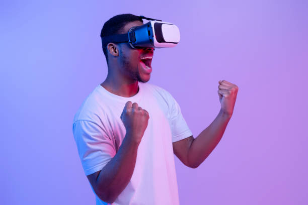 istock Excited Black Man In VR Headset Glasses Playing Cyber Games, Neon Light 1302985940