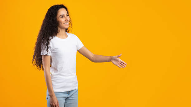istock Woman Offering Hand For Handshake Greeting Aside, Yellow Background, Side-View 1302985964