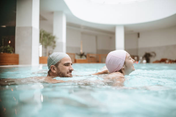 linda pareja disfrutando de nadar juntos en la piscina - sports venue luxury love enjoyment fotografías e imágenes de stock