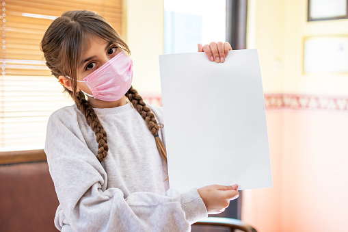 Cute student girl holding empty blank with mask