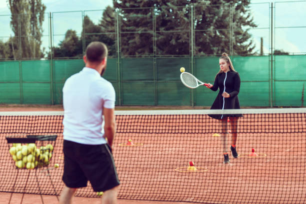istock Tennis Teacher Instructing Female Student How To Hit The Ball 1302995295