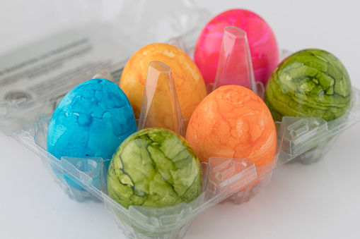 six colorful easter eggs in a box of plastic bought in a supermarket