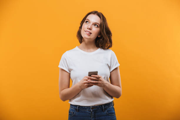 istock Cute thinking young woman chatting by mobile phone. Looking aside. 1302999411
