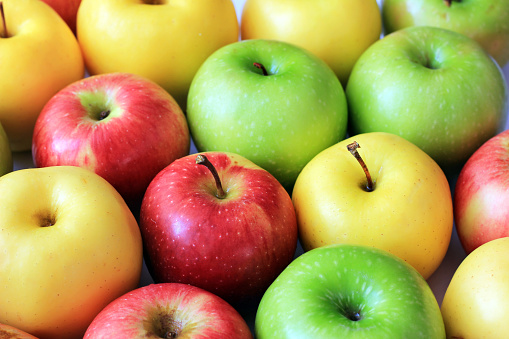 Red apple floating in mid-air, against light blue background with copy space.\nDiet concepts.