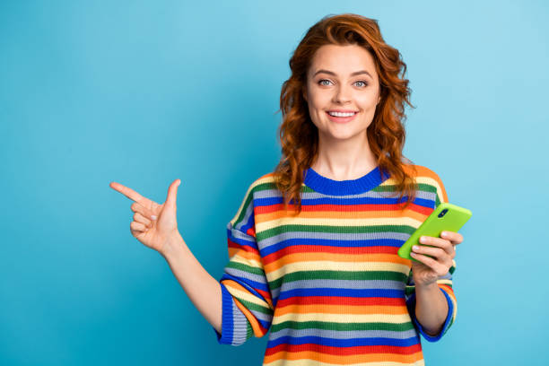 istock Photo of charming lady dressed striped pullover holding modern gadget pointing finger empty space isolated blue color background 1303004993