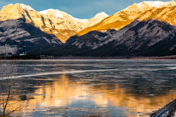 istock Sun rises over the lake and reflects the mountains. Lac de Arc, Alberta, Canada 1303006659