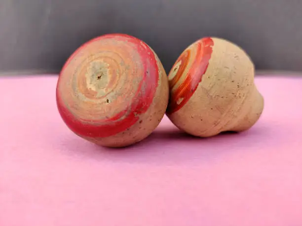 Side view of two small wooden spinning top toys isolated on pink background