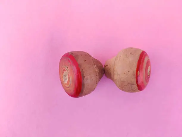 Top view of two small wooden spinning top toys isolated on pink background