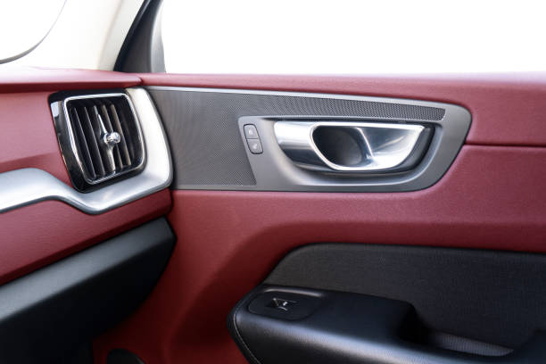 istock Car door handle inside the luxury modern car with red leather texture with stitching. Switch button control. Modern car interior details. Red perforated leather 1303007914