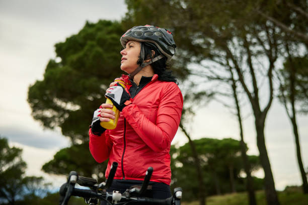 istock Mature Female Cyclist Taking a Water Break During Training 1303009749