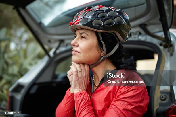 Early 50s Female Athlete Putting On Cycling Helmet Stock Photo - Download Image Now - Cycling Helmet, One Woman Only, Put On