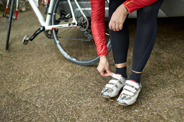 спортсменка надевая велосипедную обувь перед тренировкой - cycling bicycle triathlon women стоковые фото и изображения