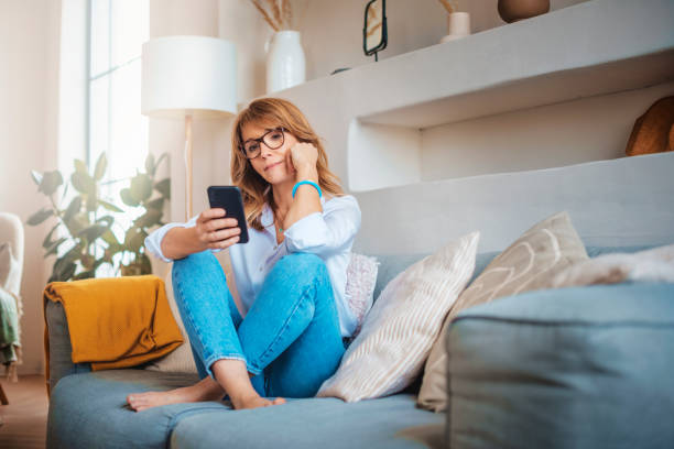 istock Mature woman text messaging while relaxing on the couch at home 1303010691