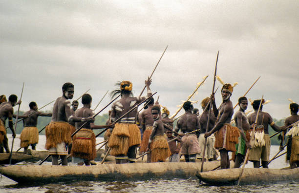 Woman beating a hand-made drum as part of a tribal ceremony. Papua New Guinea.