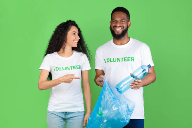 istock Diverse Volunteers Putting Plastic Bottle To Garbage Bag, Green Background 1303013189