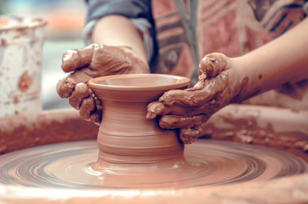 istock Hands of a potter at work. Potter making ceramic mug on the pottery wheel 1303016617